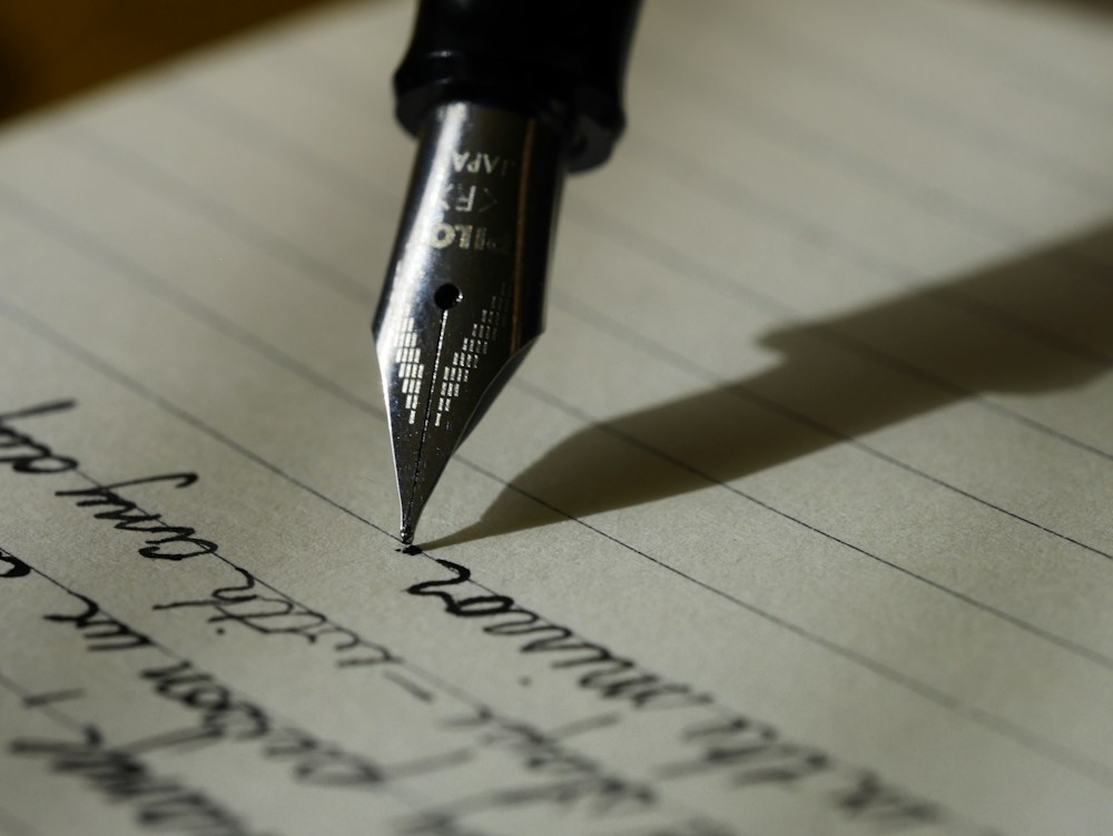 Writer shaping a thoughtful message by hand in an open notebook